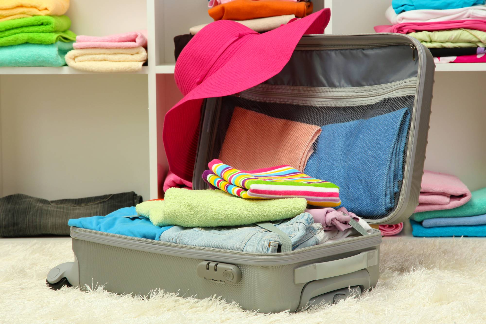 open silver suitcase with clothing in room